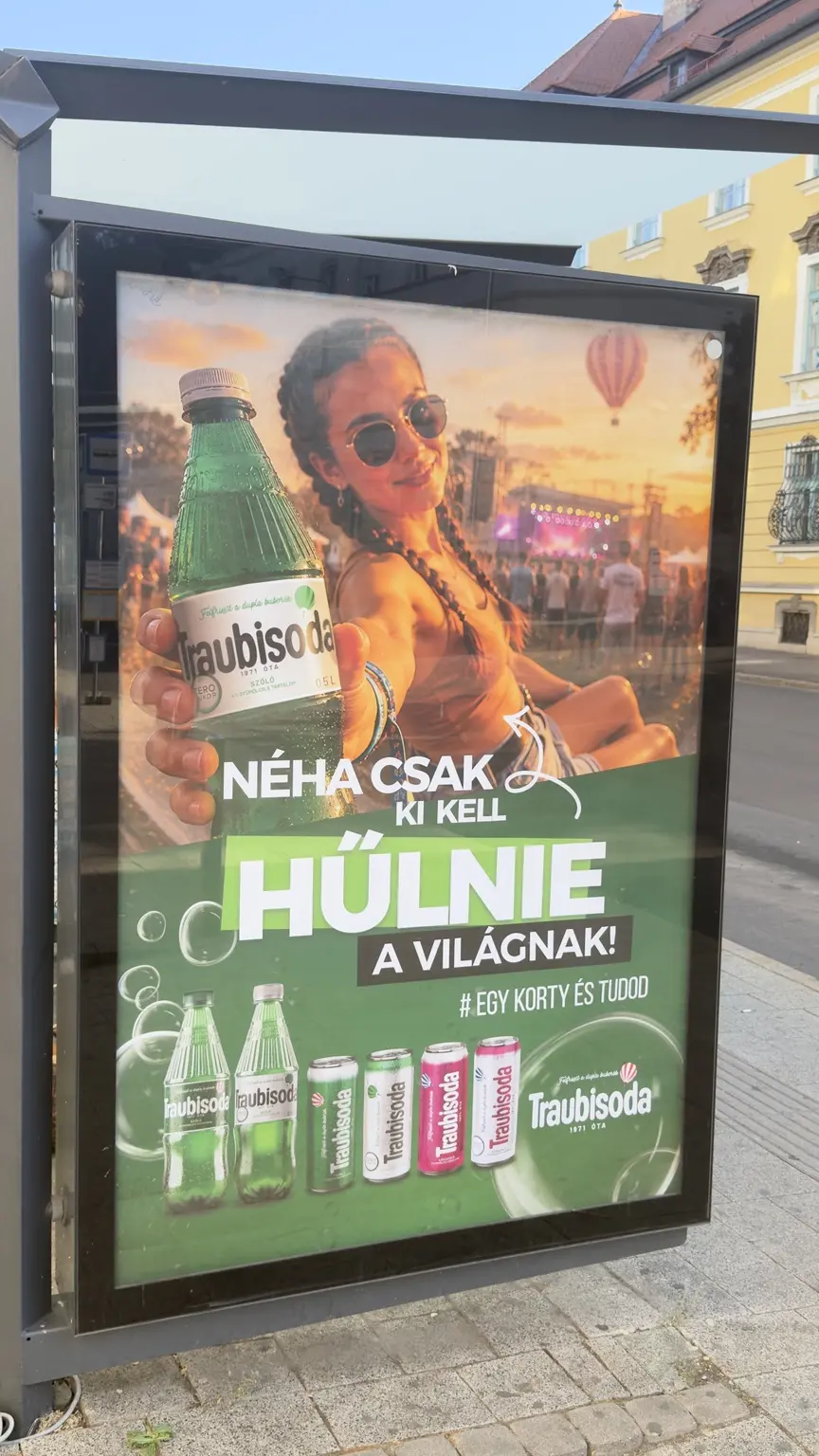 Traubisoda közterületi hirdetése fesztiválképpel, előrenyújtott zöld palackkal és a lehűlésre utaló szlogennel