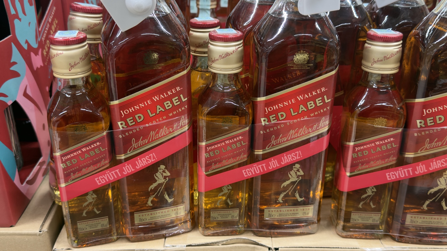 Kisebb és nagyobb Johnnie Walker Red Label üvegek közös piros csomagpántban, az Együtt jól jársz! felirattal.